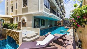 Una piscina con sillas al lado de un edificio. en Cozy 2 Bedrooms - The Lago Nai Harn by AHP, en Rawai Beach