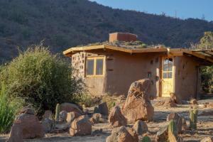 a house in the desert with rocks in front of it at Refugio de tierra con vistas en Ocoa in Viña Guzmán