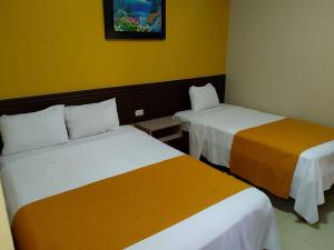 Dos camas en una habitación con paredes amarillas. en Hotel Lanus, en Portoviejo 7 fotos más