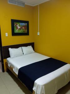 1 dormitorio con 1 cama grande en una pared amarilla en Hotel Lanus, en Portoviejo