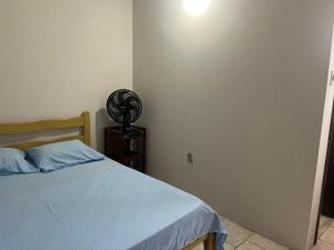 a bedroom with a bed and a fan on a night stand at Pousada Sossego in Pojuca