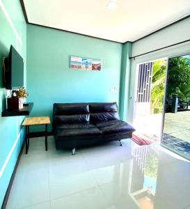 365 Place Maikhao في Ban Mai Salae: أريكة جلدية سوداء موجودة في غرفة المعيشة
