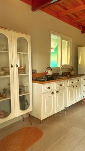 cocina con armarios blancos y encimera en Cabana dos Coqueiros Para-tí, en Taquara