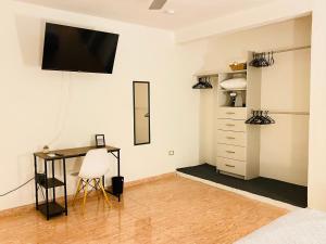 Casa Montejo a 5 min del Centro Histórico, 8 personas في ميريدا: غرفة بها مكتب وتلفزيون على الحائط