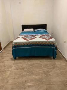 FELIZ ESTADIA Via PRINCIPAL PUERTO LOPEZ في بويرتو لوبيز: سرير في غرفة نوم مع أرضية من البلاط