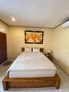 una camera da letto con un letto e un dipinto sul muro di MALINI Homestay ad Ubud