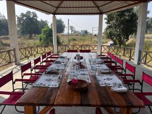 une grande table en bois avec des chaises et des assiettes. dans l'établissement Home in the Jungle, à Seonī