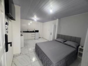 een kleine slaapkamer met een bed en een keuken bij Studios Cordeiros in Itajaí