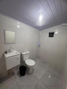 een witte badkamer met een toilet en een wastafel bij Studios Cordeiros in Itajaí