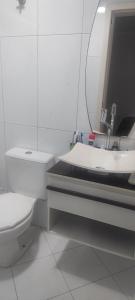 Un baño con inodoro, lavabo y espejo. en Suíte na rua da praia, en Porto Belo