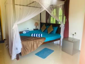 a bedroom with a blue bed with a canopy at Deshan Homestay & Restaurant in Tangalle