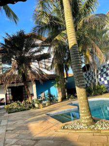 un complexe avec un palmier et une piscine dans l'établissement Pousada Preziosa Beach Itanhaém, à Itanhaém