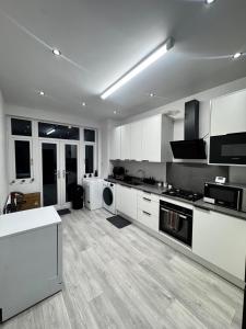 a large kitchen with white cabinets and appliances at The Central Haven in Manchester