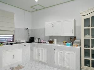 a white kitchen with white cabinets and appliances at Soi Saliga in Rawai Beach +8 photos