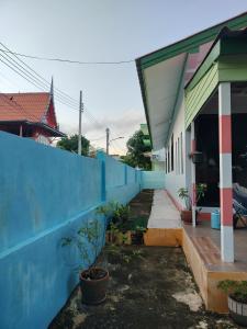 a building with a blue wall and a sidewalk at Soi Saliga in Rawai Beach