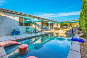 a swimming pool with chairs and umbrellas next to a house at Turquoise Mirage Fun House in Indio