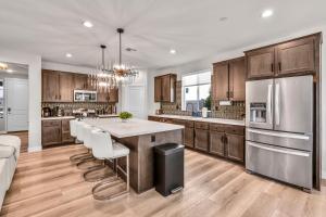 a kitchen with wooden cabinets and a kitchen island with white chairs at Turquoise Mirage Fun House in Indio