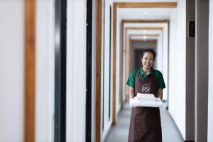 a man holding a stack of towels in a hallway at RS1 Hotel--Near Wattay International Airport in Ban Pho Touane
