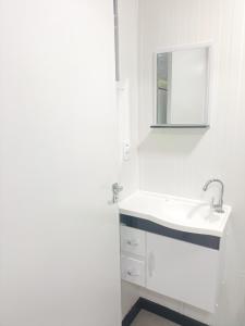 a white bathroom with a sink and a mirror at Studio Borboletas de luz in Bombinhas +19 photos