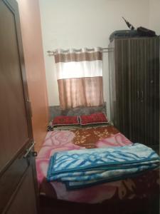 Una cama pequeña en una habitación con ventana. en Nagaraj, en Hampi