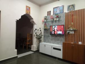 Una sala de estar con un televisor en la pared. en Nagaraj, en Hampi