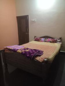 Una cama en un dormitorio con una manta morada. en Nagaraj, en Hampi
