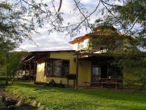 una casa amarilla con un patio verde delante de ella en Vista del Mar Casa y Bungalows en Máncora