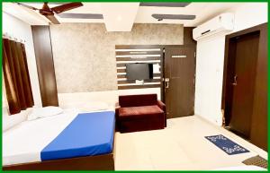 a bedroom with a bed and a chair and a tv at Mahakaleshwar jyotilinga Temple Dwarika - Dhish Premium near Railway station, Fully Air conditioned Rooms -wifi- Lift and Restaurant Facilities, BEST HOTEL IN UJJAIN in Ujjain
