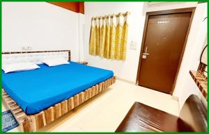 a bedroom with a blue bed and a door at Mahakaleshwar jyotilinga Temple Dwarika - Dhish Premium near Railway station, Fully Air conditioned Rooms -wifi- Lift and Restaurant Facilities, BEST HOTEL IN UJJAIN in Ujjain +1 photo