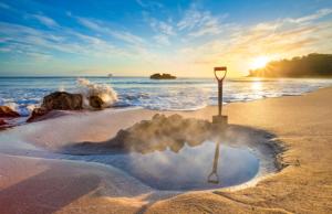 a pile of snow on a beach with a sign in the sand at Tairua Getaway in Tairua