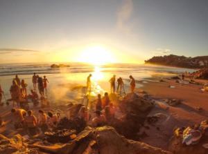a group of people on a beach at sunset at Tairua Getaway in Tairua