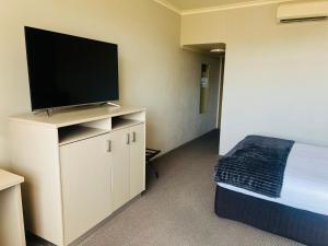 ワガワガにあるPavilion Hotel Wagga Waggaのベッドと薄型テレビのある寝室