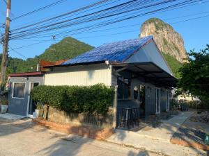 a house with a solar roof with a mountain in the background at Phunara Guest House in Phatthalung