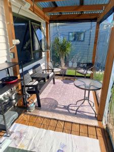 a screened in porch with a table and chairs at Riverview Studio in Te Puru