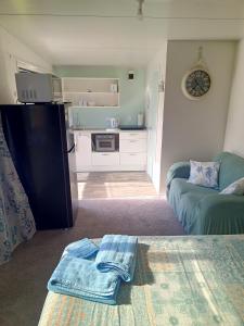 a living room with a couch and a kitchen at Riverview Studio in Te Puru