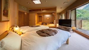 a large bedroom with two beds and a flat screen tv at Hakkei in Maniwa