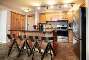 een keuken met houten kasten en een bar met krukken bij Rocky Mountain Retreat-Mountain View! in Canmore