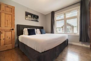 een slaapkamer met een groot bed met een groot raam bij Rocky Mountain Retreat-Mountain View! in Canmore