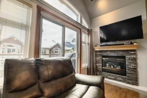 een woonkamer met een leren bank en een open haard bij Rocky Mountain Retreat-Mountain View! in Canmore