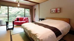 a bedroom with a bed and a chair and a window at Hakkei in Maniwa