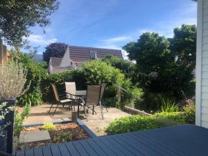 a patio with a table and chairs in a garden at Cambria Cottage in Nelson