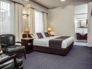 a hotel room with a bed and a chair at Mercure Ballarat Hotel & Convention Centre in Ballarat +61 photos
