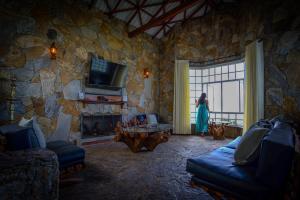 a woman standing in a living room with a stone wall at The Colonial Crest in Nillambe