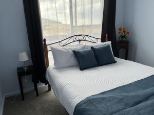 a bed with blue and white pillows and a window at Pelicans Perch in Mannum