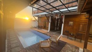 a house with a swimming pool with chairs and a balcony at Ndalem Argupta in Kalibeber