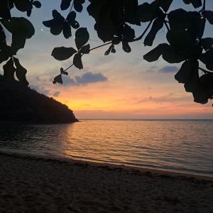 a view of the ocean at sunset from the beach at ocam ocam cottages in Busuanga +3 photos