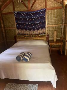 a bed in a room with two pillows on it at ocam ocam cottages in Busuanga