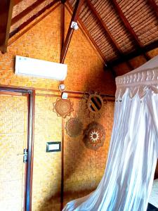 a room with a curtain and a brick wall at Kampung Meno Bungalows in Gili Meno
