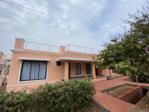 Sea view villa في Harnai: منزل وردي مع شرفة فوقه