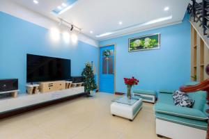 Hoang Long Home في فنغ تاو: غرفة معيشة زرقاء مع أريكة وتلفزيون